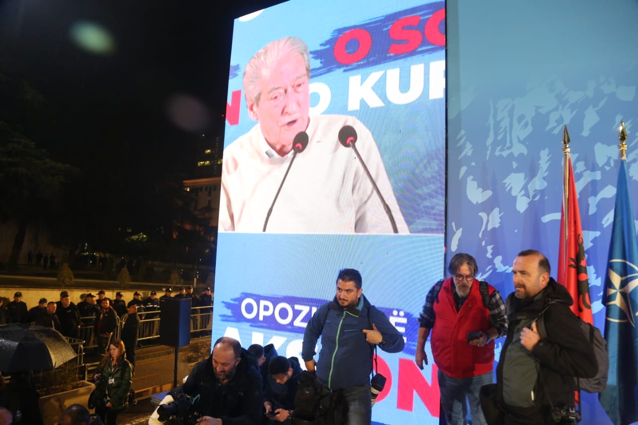 Lideri i PD, Sali Berisha duke i folur opozitarëve nga ekranet e vendosura në podium 